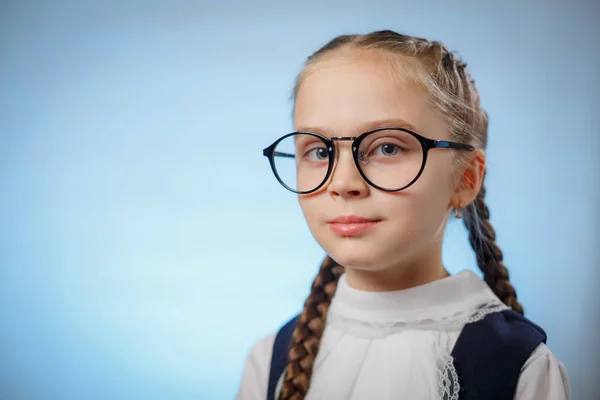 Retrato de uma menina encantadora estudante em óculos em um fundo azul — Fotografia de Stock