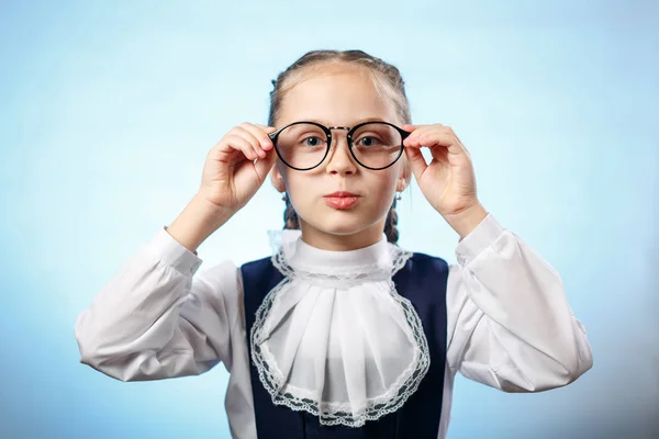 Linda colegiala tratar gafas en fondo azul —  Fotos de Stock