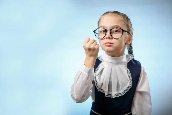 Schattig basisschoolmeisje maken vuist blauwe achtergrond — Stockfoto