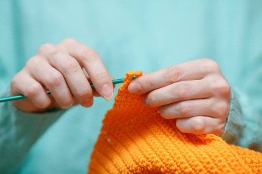 Kadın El Örgü Yün Süveteri 'ni kapatın. Hobi olarak Kanca ile Parlak Turuncu İplik ören kadın. Ev yapımı el yapımı ön cephede çalışan hasta kadın. Yaratıcı Tığ İşlemesi