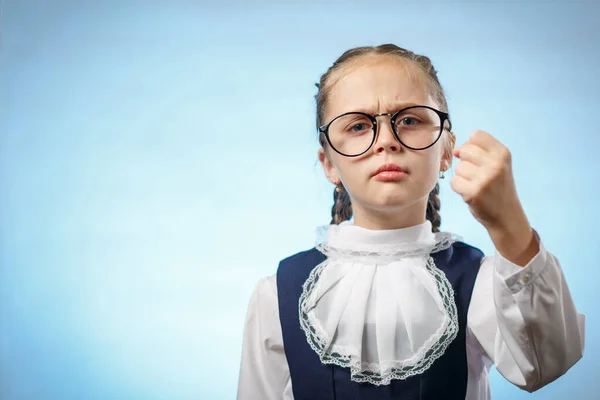 Linda primaria colegiala hacer puño azul fondo —  Fotos de Stock