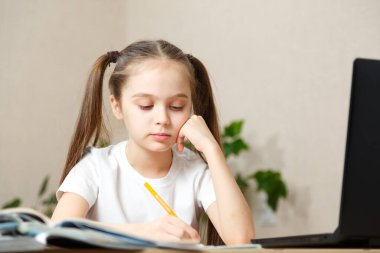 Evde online dersi, online eğitimi ve online okul konsepti sırasında ev ödevi okuyan liseli kız. Uzaktan öğrenme