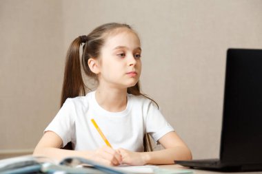 Evde online dersi, online eğitimi ve online okul konsepti sırasında ev ödevi okuyan liseli kız. Uzaktan öğrenme