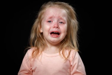 Siyah arka planda ağlayan sarışın bir kızın portresi.