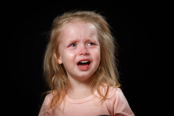 Портрет плачущей блондинки на черном фоне
