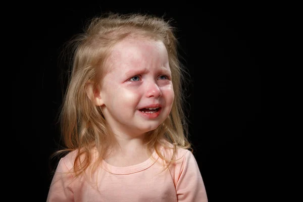 A little girl is crying hysterically in a dark room. She was badly hurt