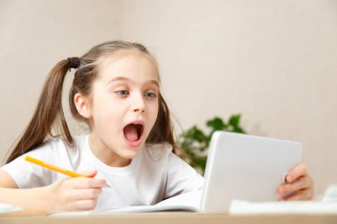 Uzaktan öğrenme çevrimiçi eğitim. Okul kızı evde tabletle ödev yapıyor. Karantina