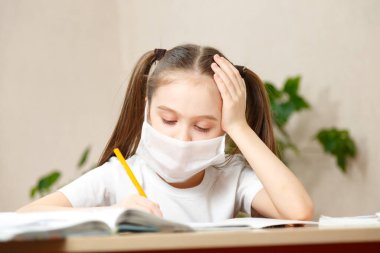 Uzaktan öğrenme çevrimiçi eğitim. Tıp maskeli kız evde ders çalışıyor.,