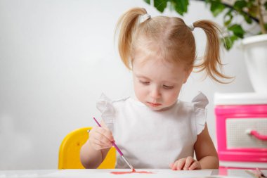 Sulu boyayla resim yapmayı öğrenen sevimli bir bebek. Evde renkli fırçalar kullanarak resim çizen küçük bir çocuk. Sağlıklı, mutlu, renkler, su ya da çocuk odası deneyleri yapan bir kız..