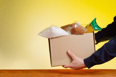 Bağış kutusunda gönüllü, sarı arka planda yiyecek var.