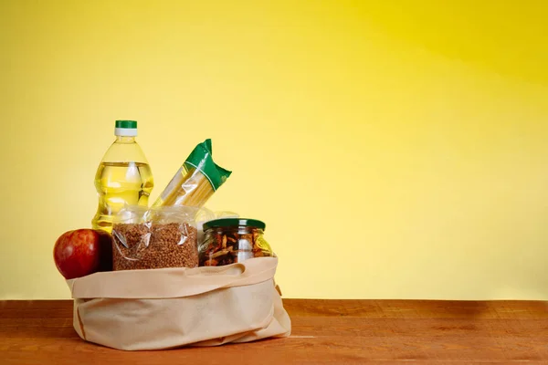 Tahta Masa 'da, Sarı Arkaplanda, Kağıt Torba İçinde Farklı Yiyecekler. Market Alışveriş Konsepti.