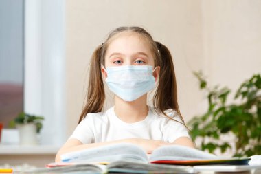 Uzaktan eğitim. Tıp maskeli kız evde ödev yapıyor. Karantina..