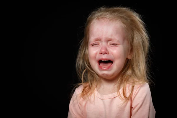 A little girl is crying hysterically in a dark room. She was badly hurt — Stock Photo, Image