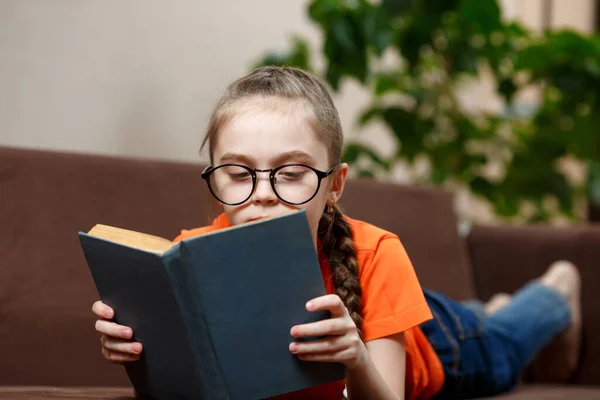 Gözlüklü Uzun Örgülü Kanepede Uzanmış Kitap Okuyan Beyaz Bir Kız — Stok fotoğraf