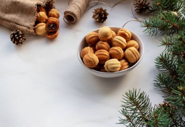 İçinde krema olan iki kabuktan yapılmış fındık şeklinde kurabiyeler. Beyaz zemin üzerinde çerezler