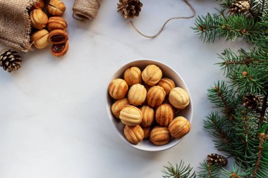 İçinde krema olan iki kabuktan yapılmış fındık şeklinde kurabiyeler. Beyaz zemin üzerinde çerezler