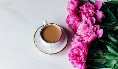 Mermer bir arka planda fincanlı kahve ve şakayık çiçekleri. Boşluğu kopyala