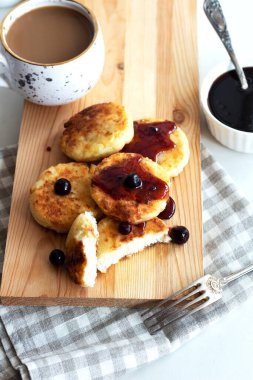 Sabah kahvaltısı var. Ahşap arka planda reçelli süzme peynirli krep. Rus, Ukrayna mutfağı.