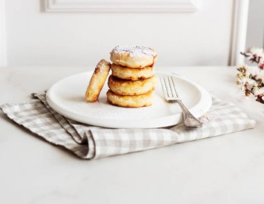 Sabah kahvaltısı var. Beyaz tabakta reçelli süzme peynirli krep. Rus, Ukrayna mutfağı. Bahar çiçekleri
