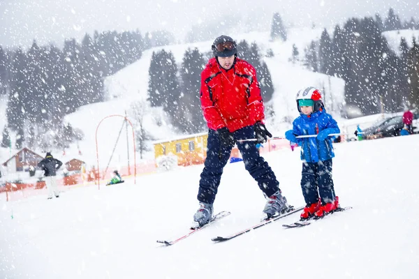 Joyeux petit garçon apprenant le ski avec son père dans les Alpes suisses — Photo