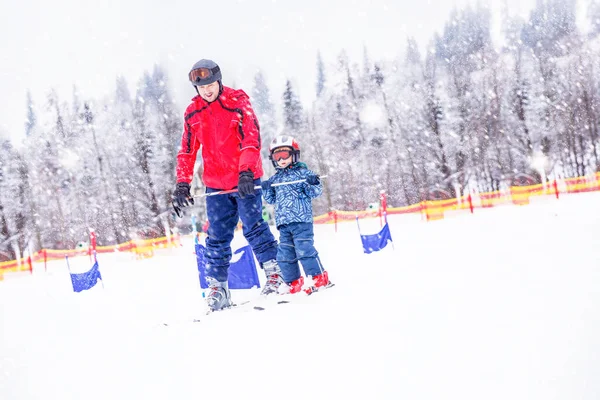 Joyeux petit garçon apprenant le ski avec son père dans les Alpes suisses — Photo