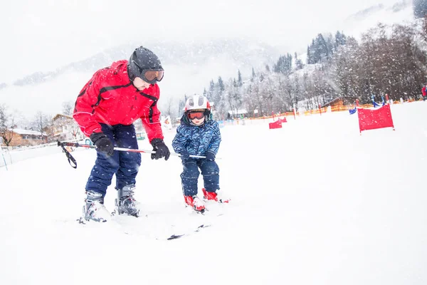 Joyeux petit garçon apprenant le ski avec son père dans les Alpes suisses — Photo