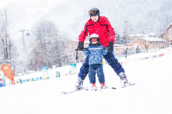 Joyeux petit garçon apprenant le ski avec son père dans les Alpes suisses — Photo
