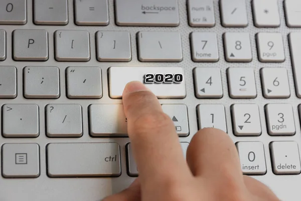 finger pressing keyboard key written 2020 new year on laptop