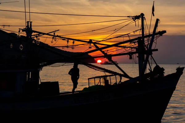 Fishermen on a boat with red sky sunset on ocean, silhouette of boat