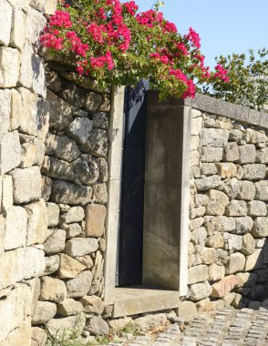 Taş duvar pembe begonvillerle 