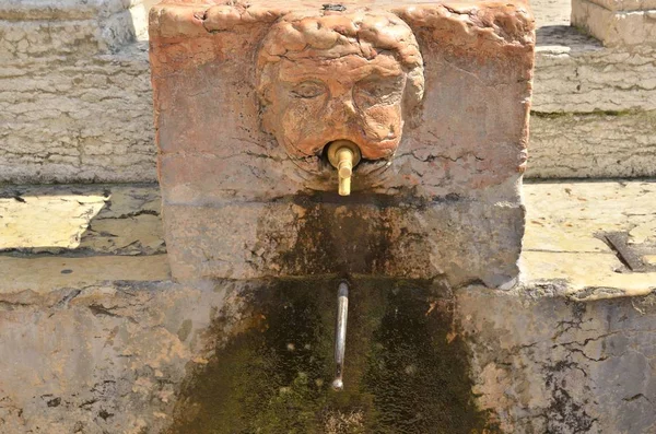 Source with sculpture of a face — Stock Photo, Image