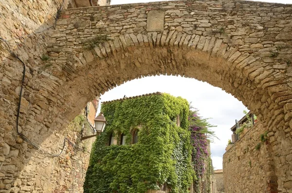 Ivy on facade seen through a stone arch  in the medieval village of Peratallada, located in the middle of the Emporda region of Girona, Catalonia, Spain.