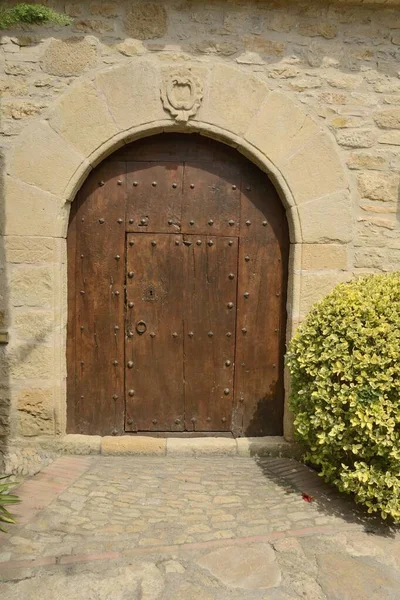 Wooden door under stone arch in the medieval village of Peratallada, located in the middle of the Emporda region of Girona, Catalonia, Spain.