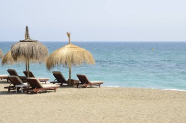 Marbella, Endülüs, İspanya sahillerinde güneş yatakları ve hasır şemsiyeler