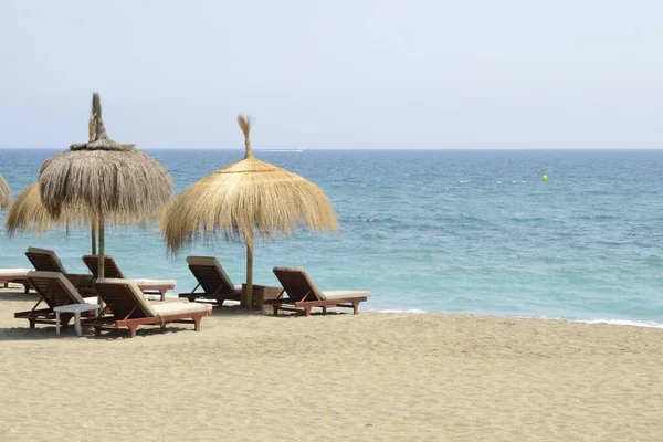 Marbella, Endülüs, İspanya sahillerinde güneş yatakları ve hasır şemsiyeler