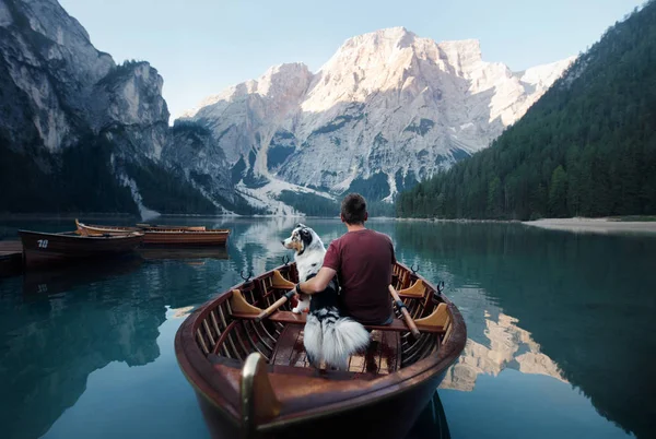 Man and dog in a boat on a mountain lake. Trip with a pet to Italy. Australian Shepherd Dog and its owner — Zdjęcie stockowe