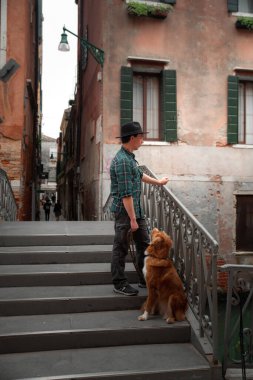 Venedik rıhtımında köpeği olan bir adam. Bir evcil hayvanla seyahat etmek. Nova Scotia Ördek Tolling Retriever