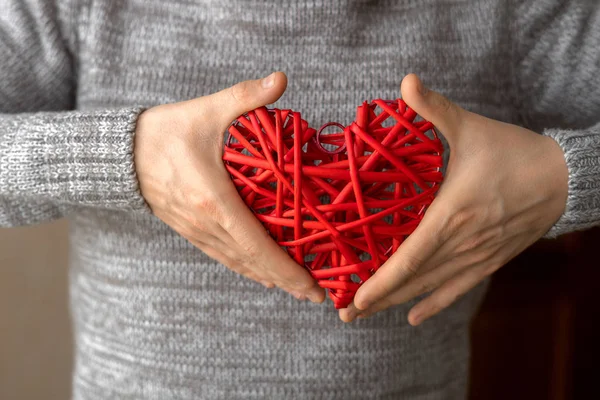 Rött flätat dekorativt hjärta i mäns händer — Stockfoto