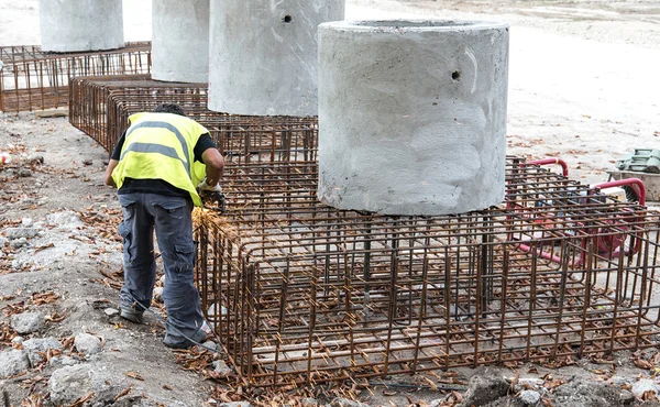 Uomo che lavora con smerigliatrice elettrica su struttura in acciaio — Foto Stock