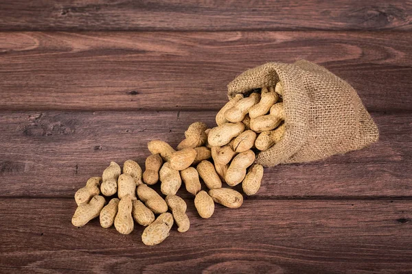 Cacahuetes en saco sobre fondo de madera — Foto de Stock