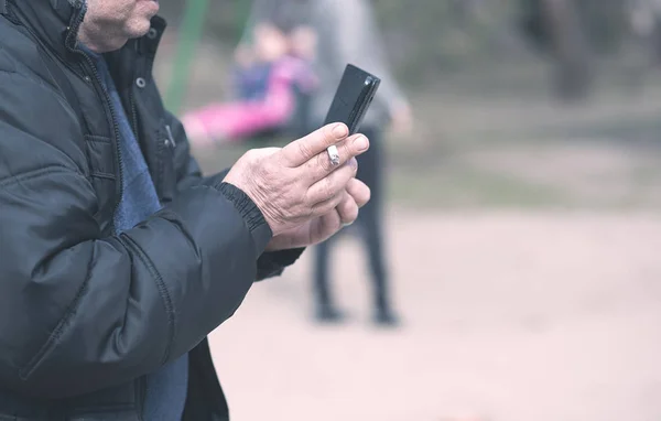 Viejo fumando y usando su teléfono — Foto de Stock