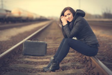 Tren rayları üzerinde oturan üzgün kadın