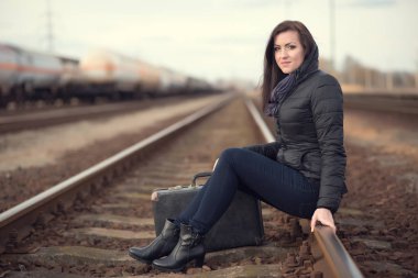 Tren rayları üzerinde oturan üzgün kadın