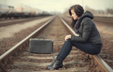Tren rayları üzerinde oturan üzgün kadın