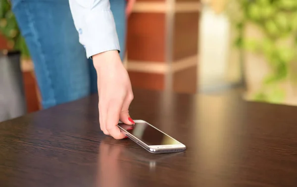 La mujer coge el teléfono de la mesa — Foto de Stock