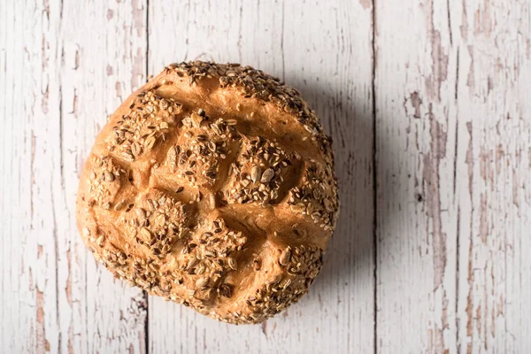 Fresh seedy bread on white wooden background — Stock Photo, Image