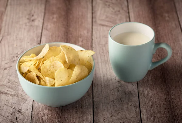 Crispy potato chips in a bowl with milk on wooden — Stock Photo, Image