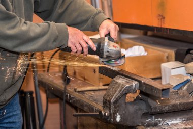 Elektrik değirmeni aracıyla çelik üzerinde çalışan adam