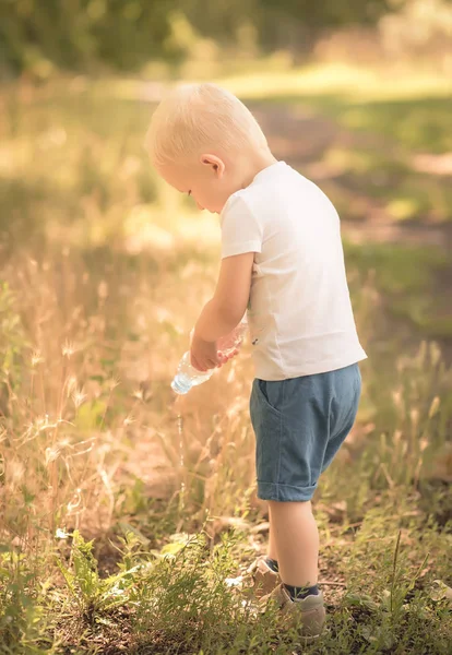 Küçük çocuk parkta çim sulama — Stok fotoğraf