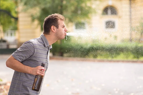 Junger Mann spuckte Alkohol aus — Stockfoto